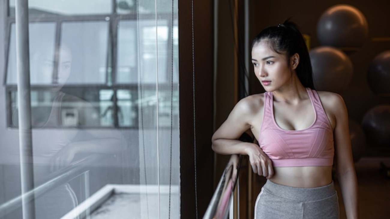 woman-standing-relaxed-hands-placed-steel-rail-gym_1150-16538